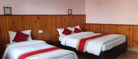 Habitación de hotel con dos camas, cabecero de madera y suelo de madera.