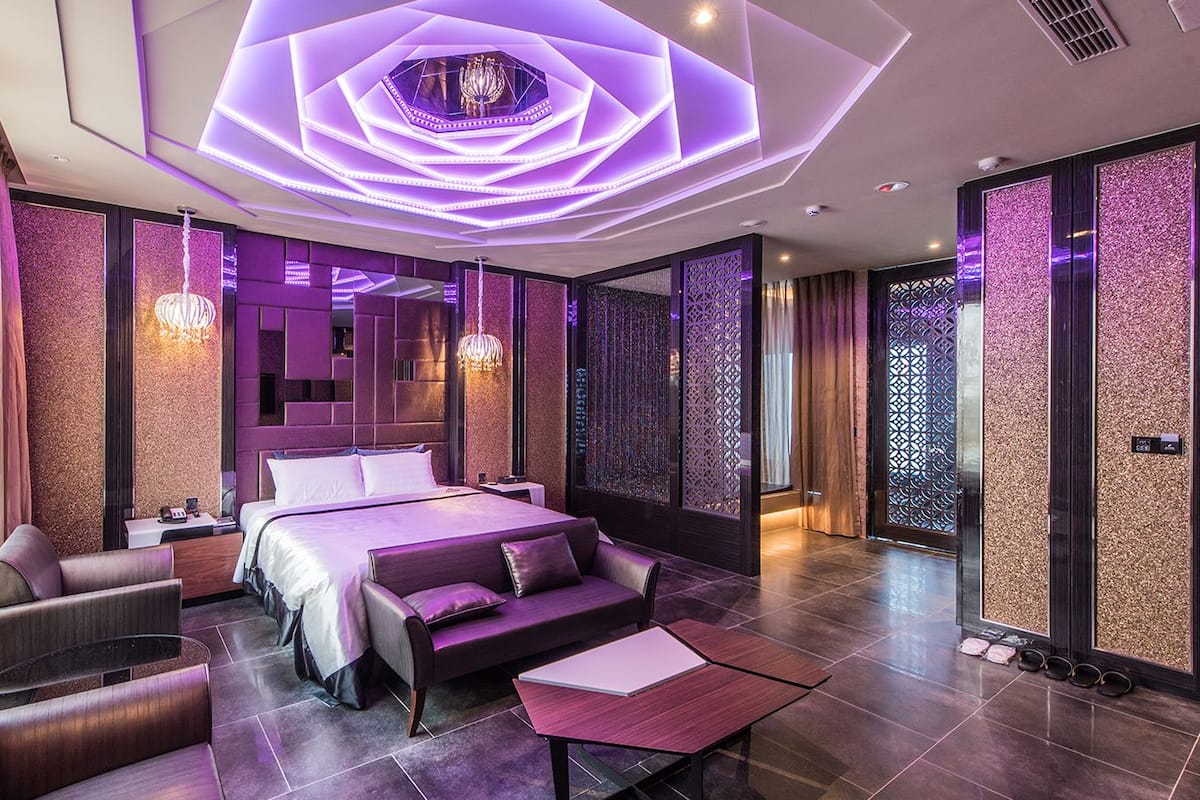 A modern hotel room with a large bed, seating area, and decorative lighting.