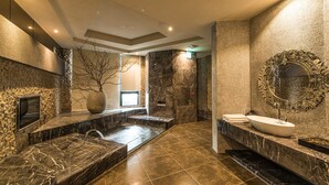 A modern bathroom with a stone wall, a large mirror, and a bathtub. - Voga Motel (Taichung)