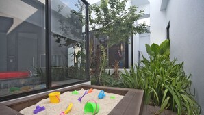 A play area with sand and toys, surrounded by plants and a glass wall. - Voga Motel (Taichung)
