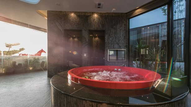 A hot tub in a modern room with a large window and a view of a tree outside. - Voga Motel (Taichung)