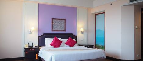 Habitación de hotel con una cama grande, dos mesitas de noche, una lámpara de pared y un cuadro en la pared.