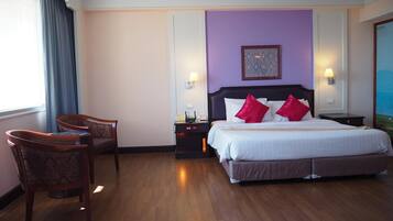 A hotel room with a large bed, two nightstands, a desk, and a chair.
