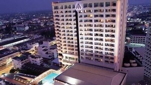 Ein Hochhaus-Hotel namens 'Charoen Thanip Princess' mit mehreren Stockwerken, einem Schwimmbad und einem Parkplatz.