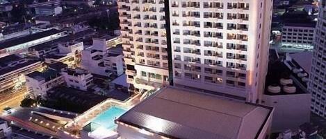 Hotel alto chamado 'Charoen Thanip Princess', com vários andares, uma piscina e área de estacionamento.