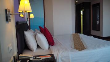 Habitación de hotel con cama, mesita de noche con lámpara, teléfono y control remoto.