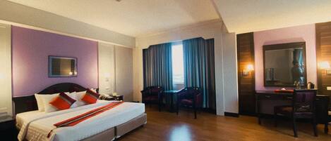 Habitación de hotel con una cama grande, dos sillas, un escritorio y un espejo.