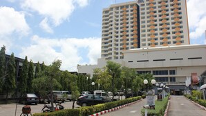 Ein mehrstöckiges Hotel mit auffälliger Beschilderung, ein Parkplatz mit mehreren Autos und einem klaren Himmel.