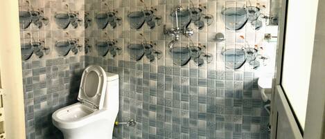 A bathroom with a toilet, patterned tiles, and multiple glass fishbowls mounted on the wall.