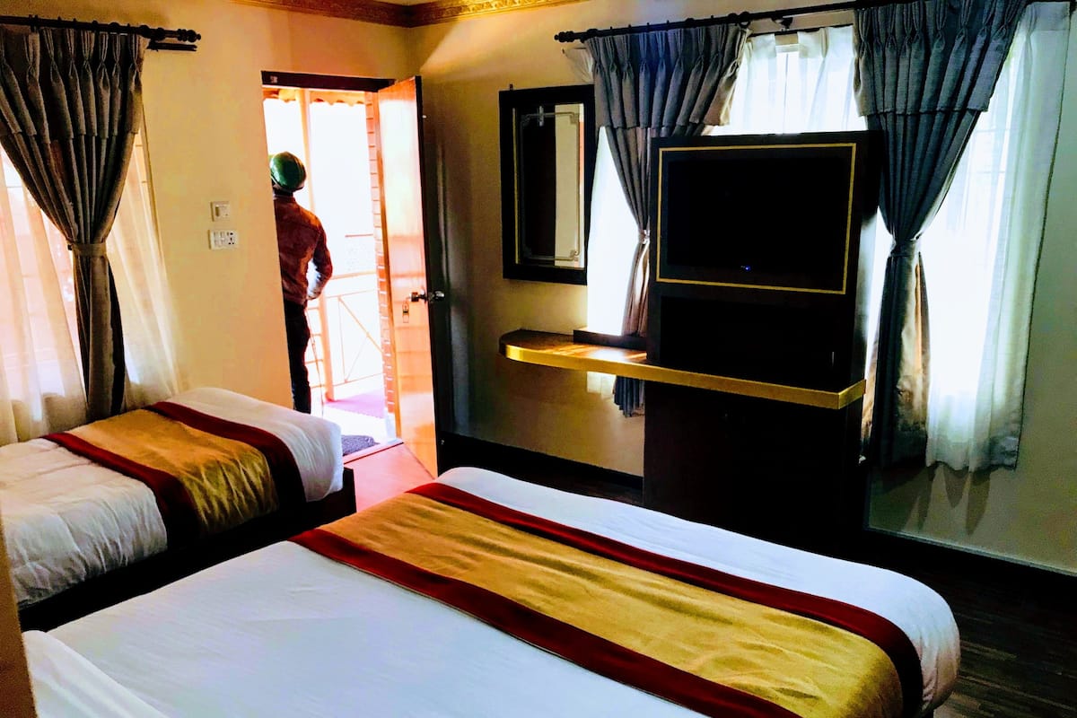 A hotel room with two beds, a television, and a mirror.