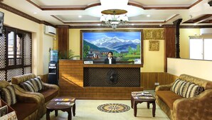 Ein Empfangsbereich mit einer Rezeption, zwei Sofas, einem Couchtisch und einem großen gerahmten Bild von Bergen.