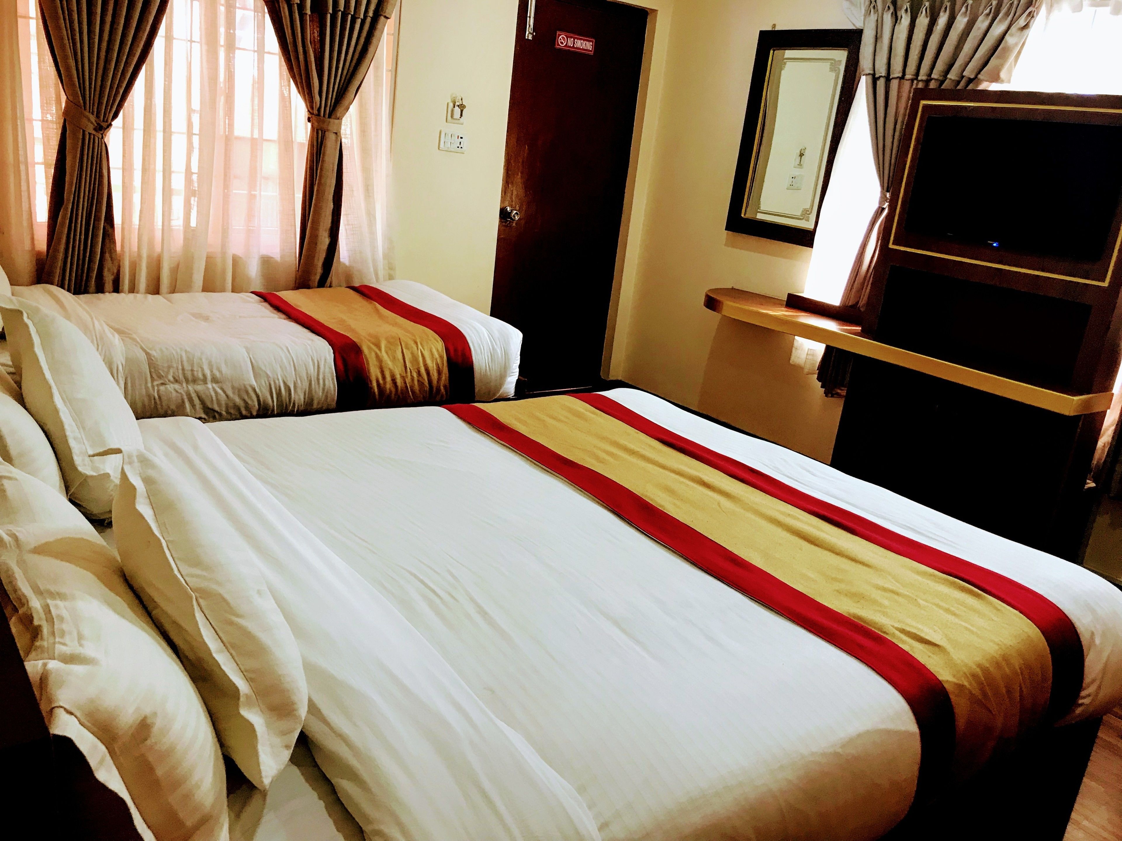 Habitación de hotel con dos camas, un televisor y una puerta con un letrero de ‘No Fumar'.