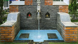 Ein Steinkonstrukt mit Wasserspeier, zwei kleinen Rundbogenfenstern und einer Ziegelstruktur.