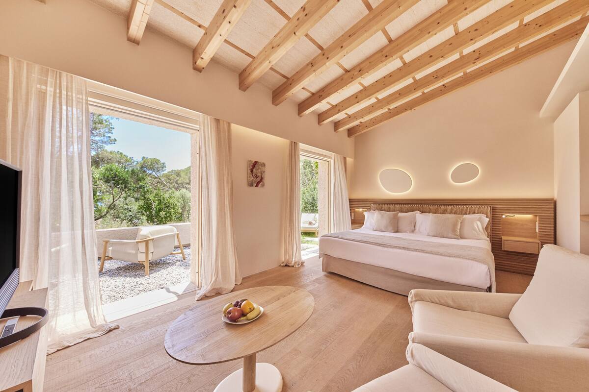 Une chambre spacieuse avec un grand lit, un coin salon avec une table et une vue sur l’extérieur.