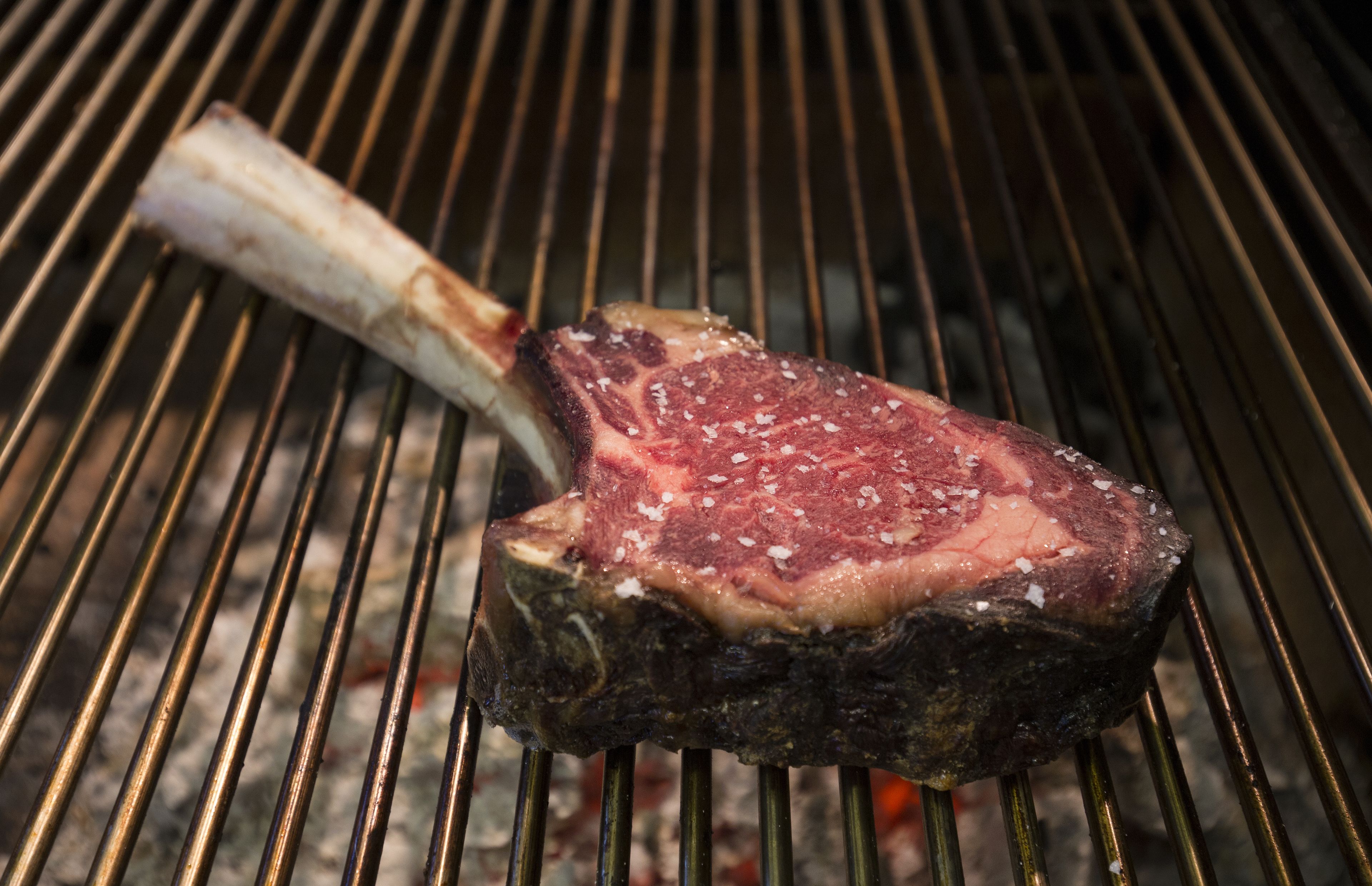 A steak on a grill with visible grill marks and a bone.