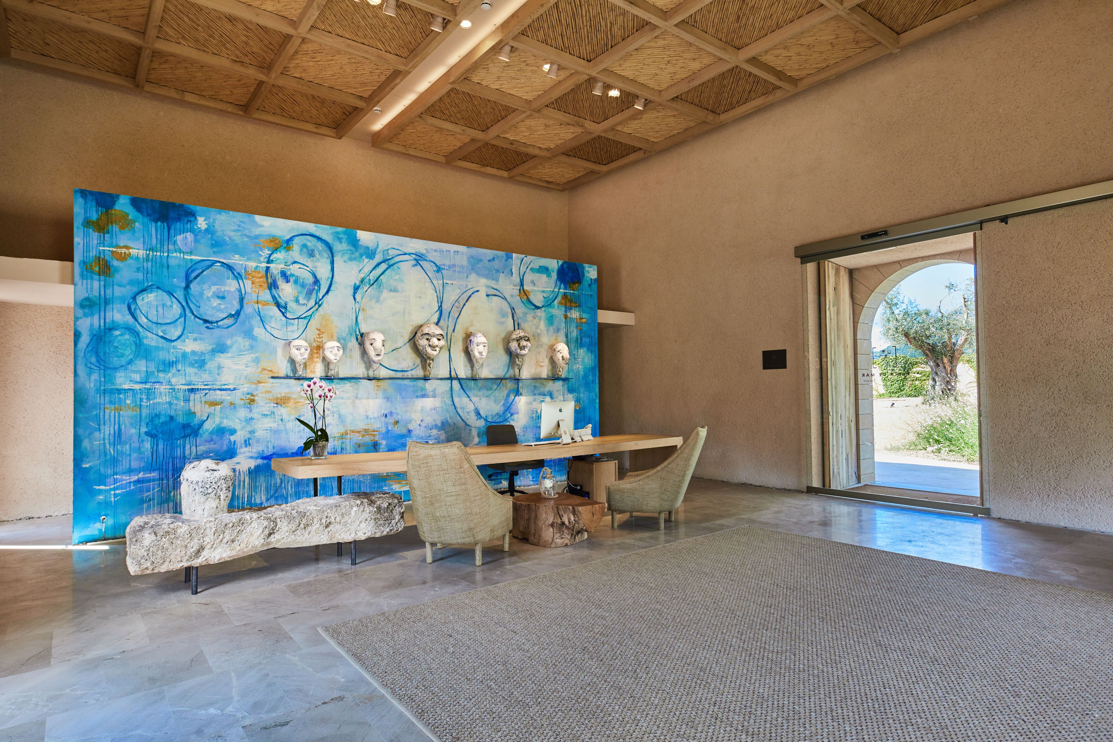 A modern interior with a large abstract painting, a reception desk, and a stone bench.