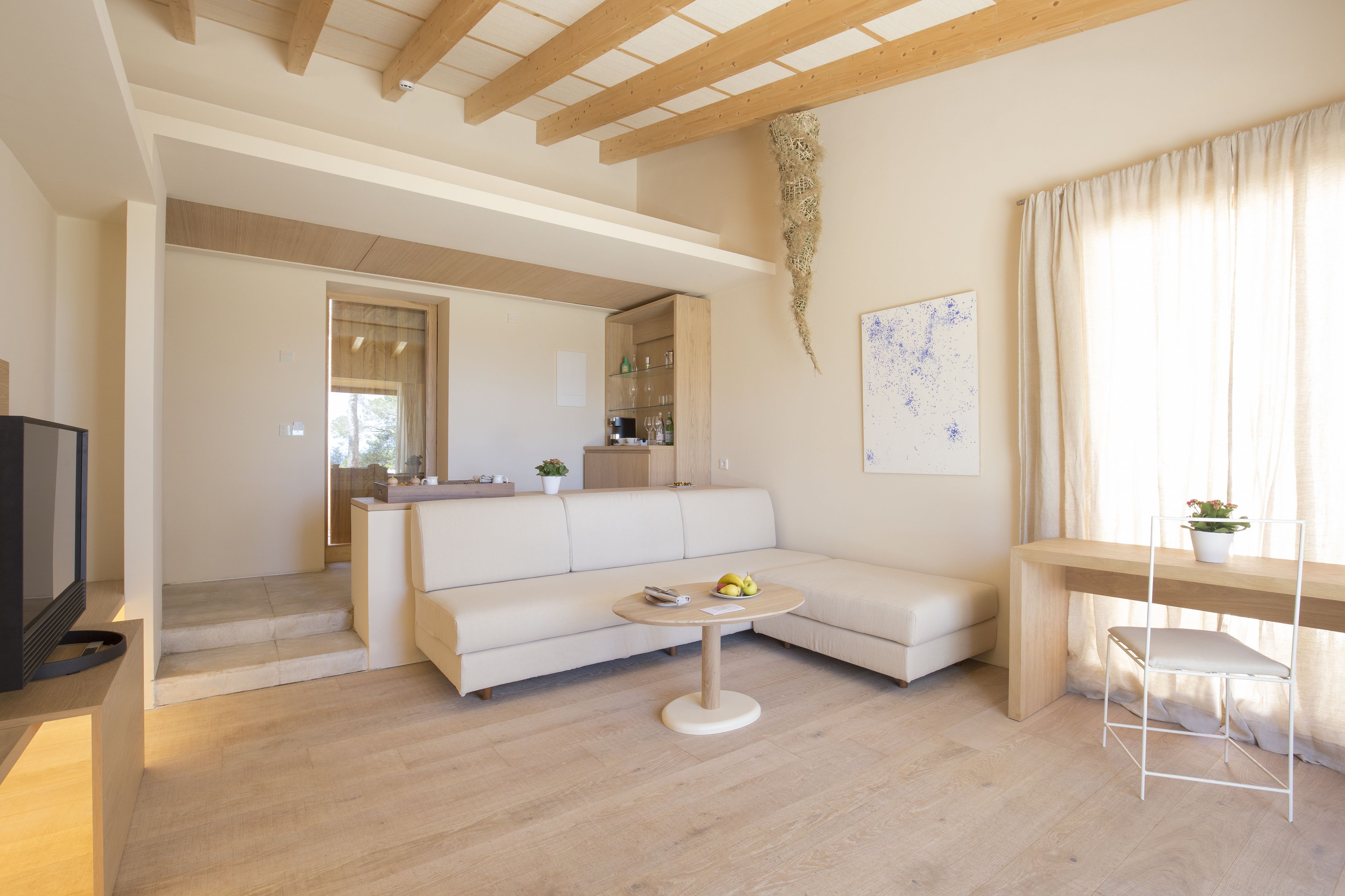A modern living room with a white sofa, a round coffee table, and a wooden desk.