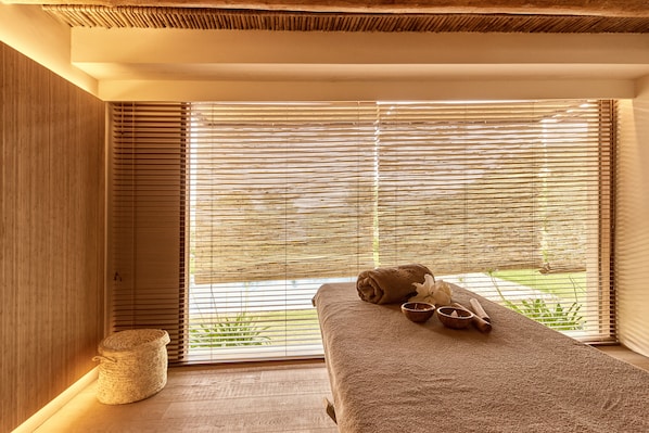 A spa room with a massage table, a towel, a bowl, and a rolled-up mat.