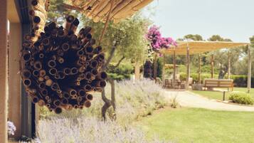 Una estructura colgante de bambú, un jardín con lavanda y un banco bajo una pérgola.