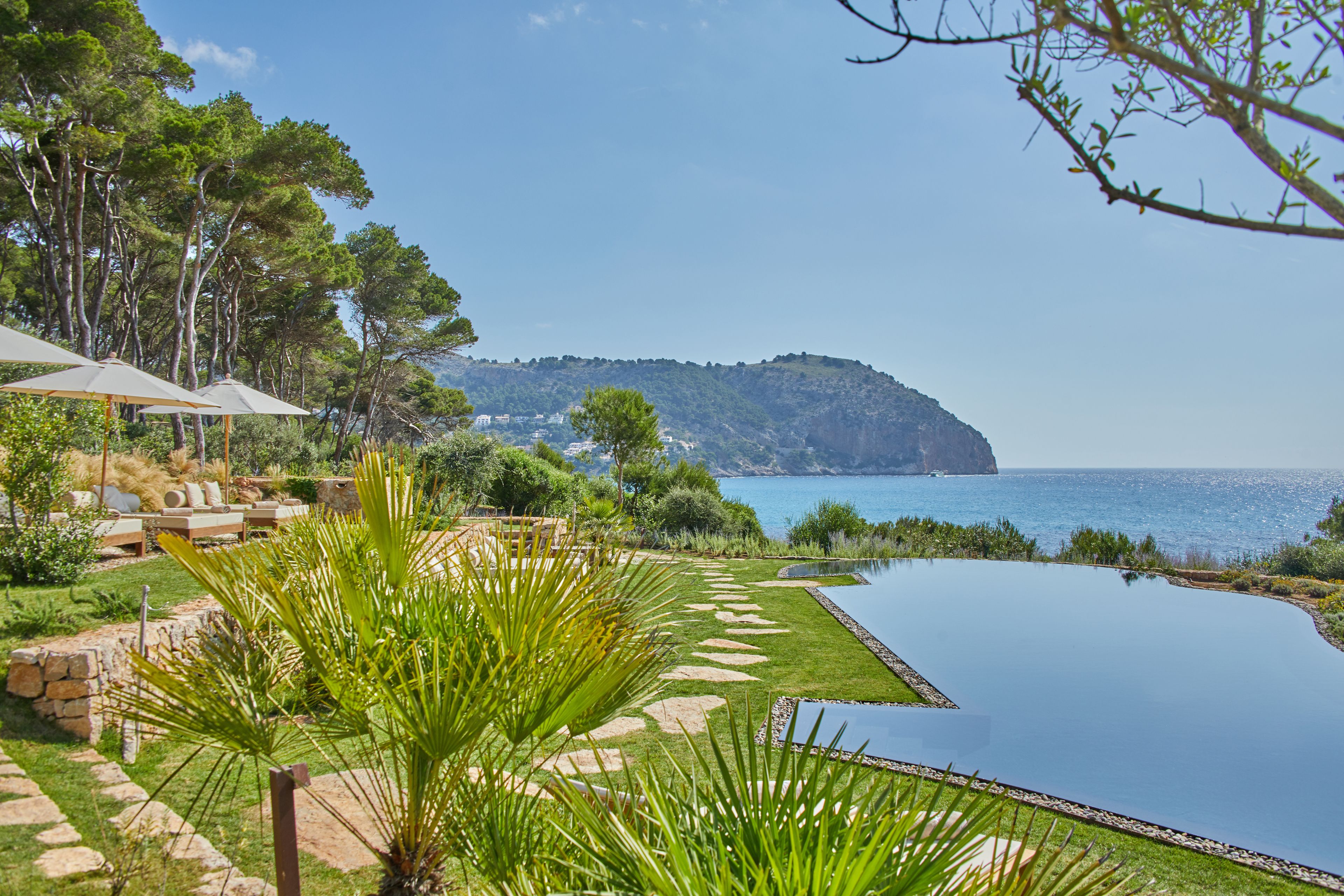 A serene outdoor setting with a swimming pool, stone pathways, and lush greenery.
