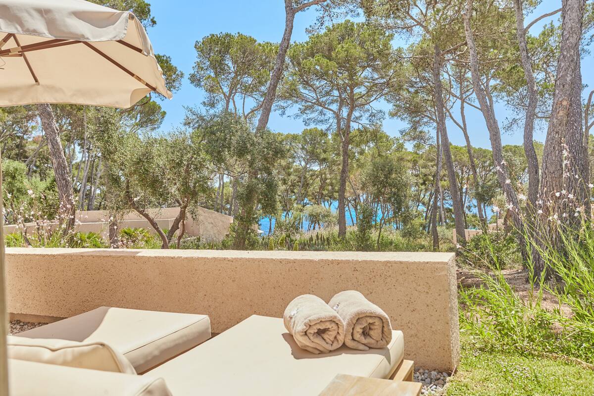 Un espace extérieur ensoleillé avec des sièges, donnant sur la piscine, comprenant des chaises longues et une serviette enroulée.