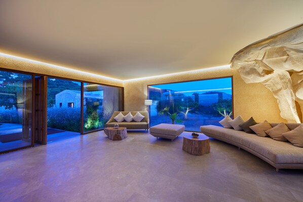 A spacious living room with a large window, a sofa, a coffee table, and a side table.