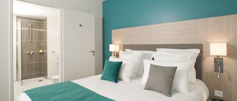 A hotel room with a bed, a shower, and a nightstand with a lamp.