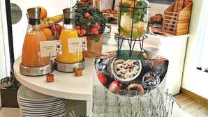 Un buffet de petit-déjeuner proposant une variété d’aliments et de boissons, notamment des fruits, des viennoiseries et un distributeur de boissons.