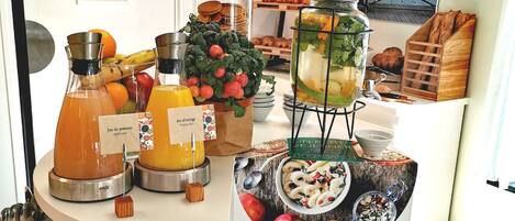 A breakfast buffet with various food items and beverages, including fruit, pastries, and a drink dispenser.