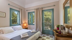 A neatly made bed with white linens and a grey blanket, a bedside table with a lamp, a tray with breakfast items, and a view of trees through the window. - Electra Beachfront Villa (Ermionida)