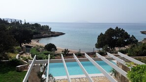 A pool with a clear view of the sea and a rocky shoreline. - Electra Beachfront Villa (Ermionida)