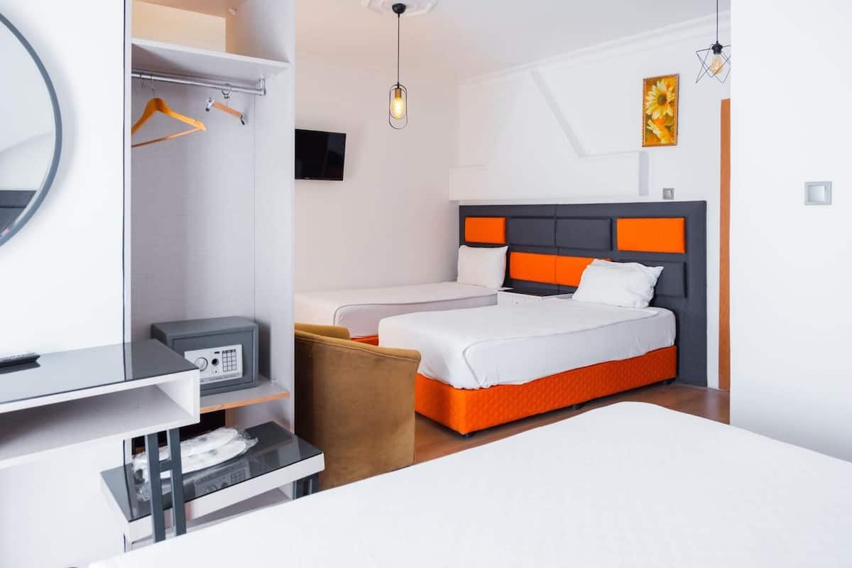 Une chambre d’hôtel comprenant un lit, un bureau avec un ordinateur, une télévision et une armoire.