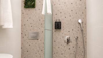 Un baño con ducha, un perchero y una pequeña planta verde en la pared.