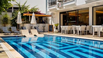 Una piscina al aire libre, sillones reclinables de piscina