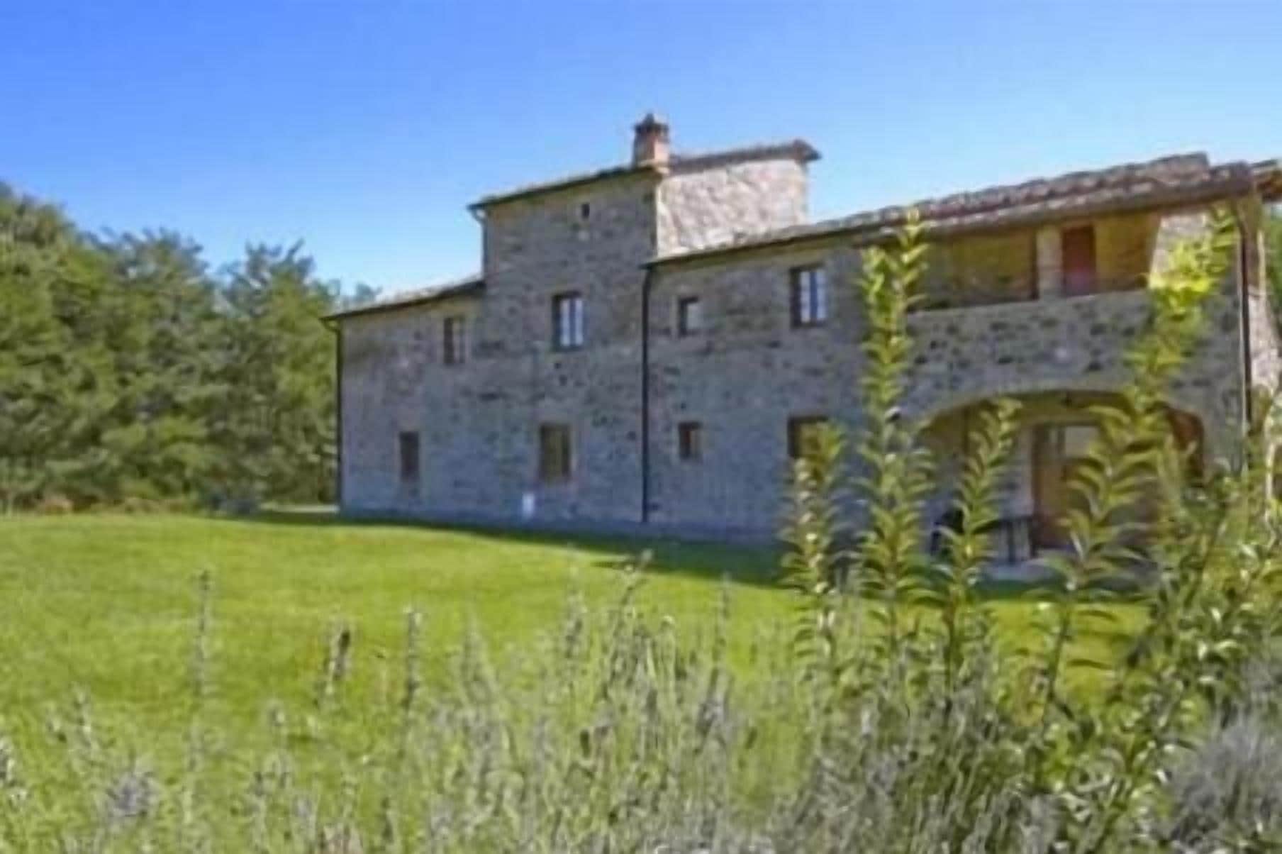 Un bâtiment en pierre avec une grande pelouse devant.