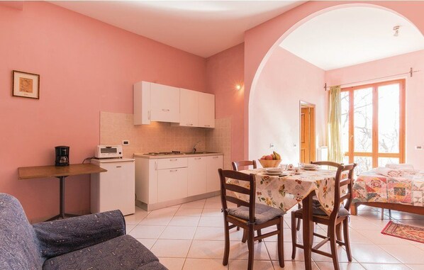 Une cuisine chaleureuse avec des meubles blancs, une table à manger avec des chaises et un canapé.