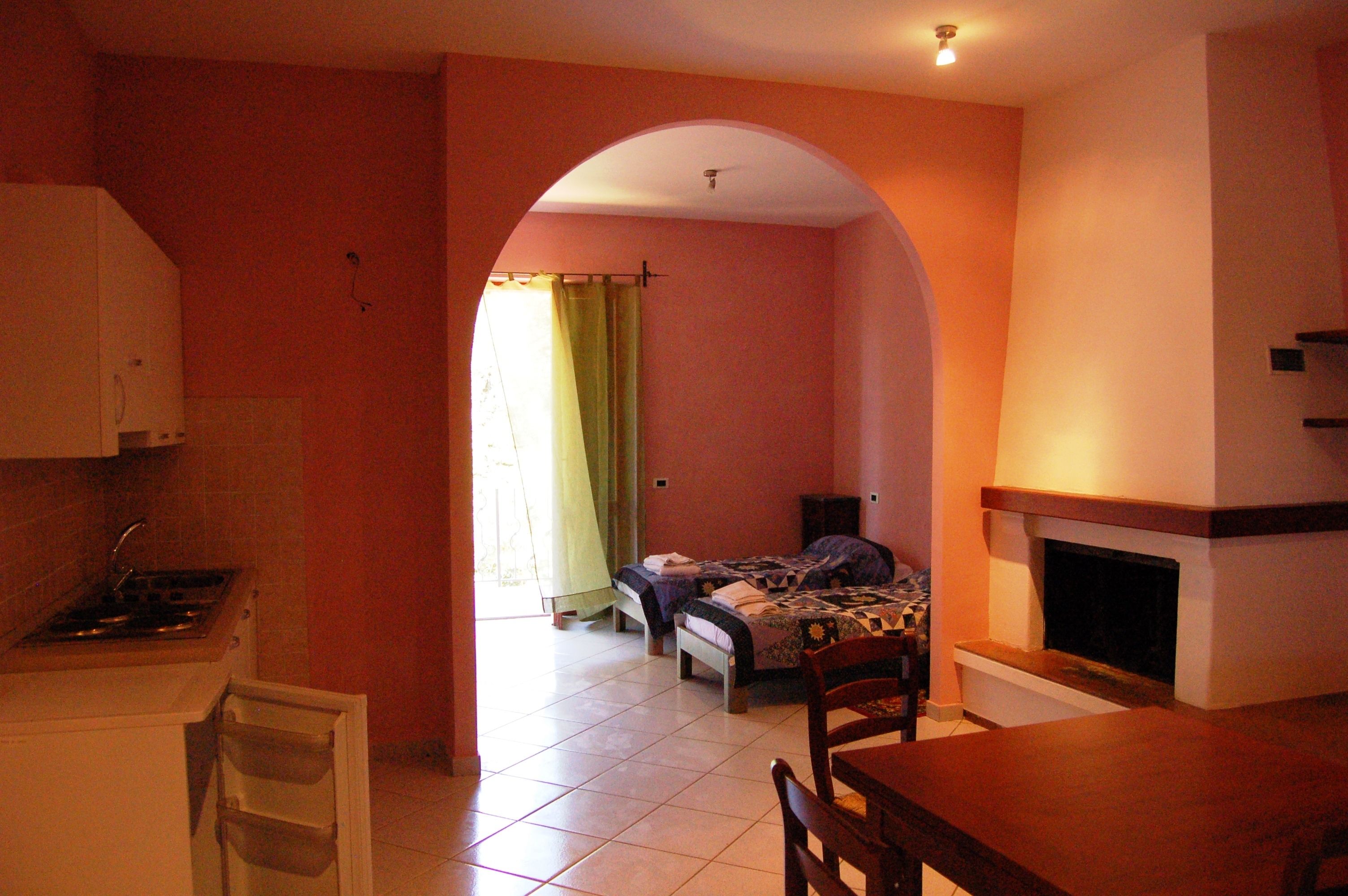 Ein kompakter Wohnraum mit Küchenbereich, Esstisch und Schlafzimmer mit Bett und Sessel.