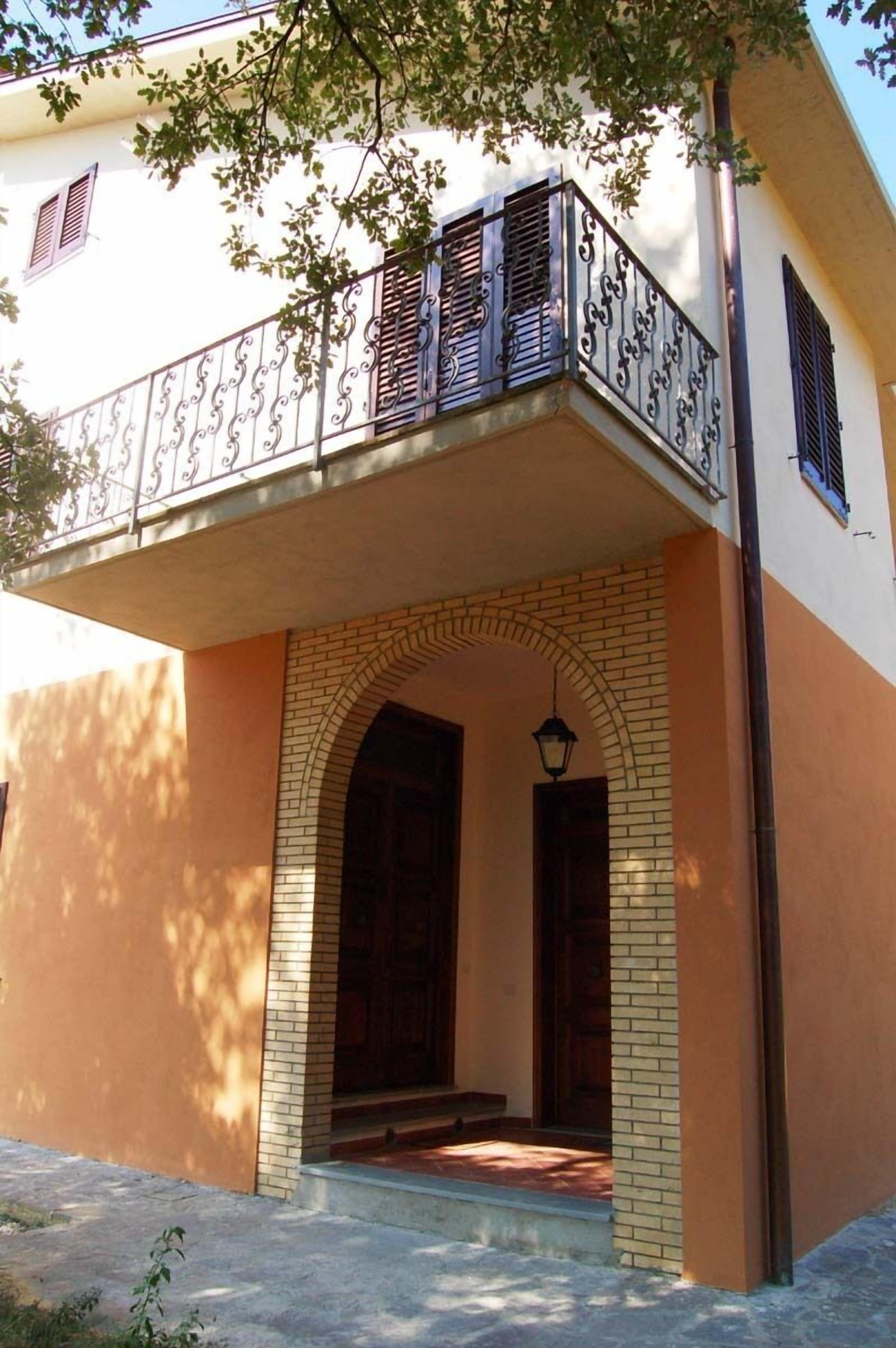 Un bâtiment doté d’un balcon, d’une arche en briques et d’une porte en bois.