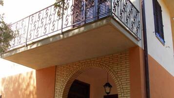 Un bâtiment doté d’un balcon, d’une arche en briques et d’une porte en bois.
