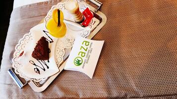 A tray with a slice of cake, a glass of coffee, and a small bottle, accompanied by a card with the logo "aza".