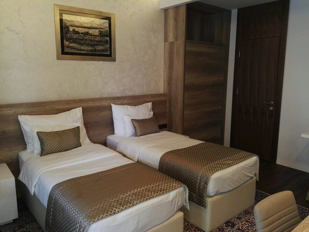 Una habitación de hotel con dos camas, un armario de madera y un cuadro en la pared.