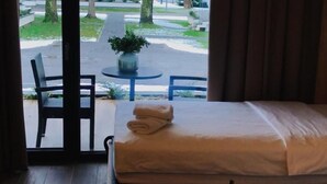 Habitación de hotel con cama, una mesita con alimentos para el desayuno y vista al exterior.