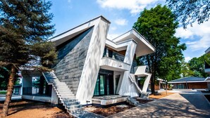 Una casa moderna con un diseño angular distintivo, que destaca una escalera imponente y amplios ventanales.