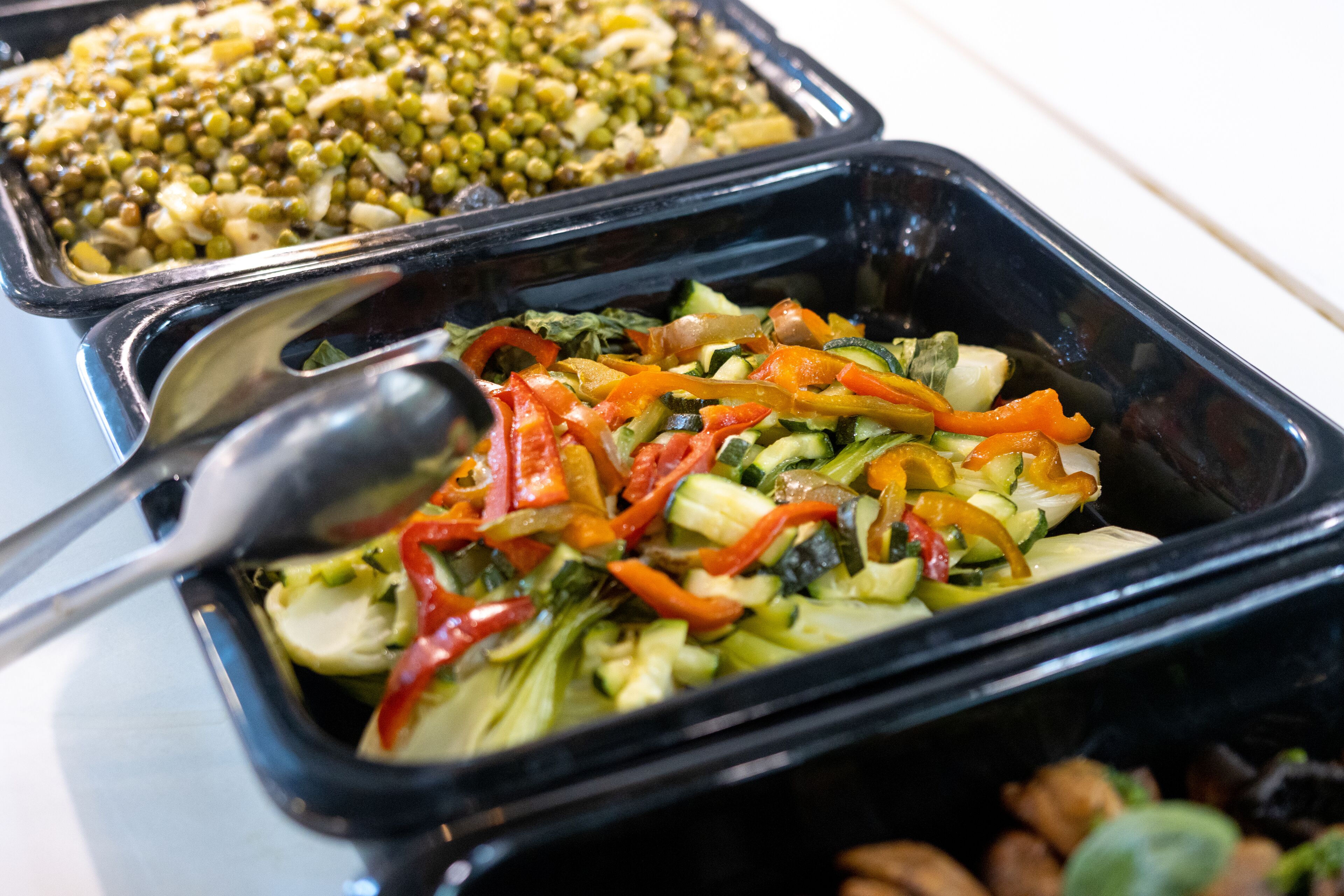Un bufé con diversos platos, incluyendo una ensalada de verduras variadas y un recipiente con cereales mezclados.