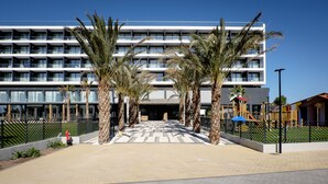 Un hotel moderno con un patio central, palmeras y un área de juegos.