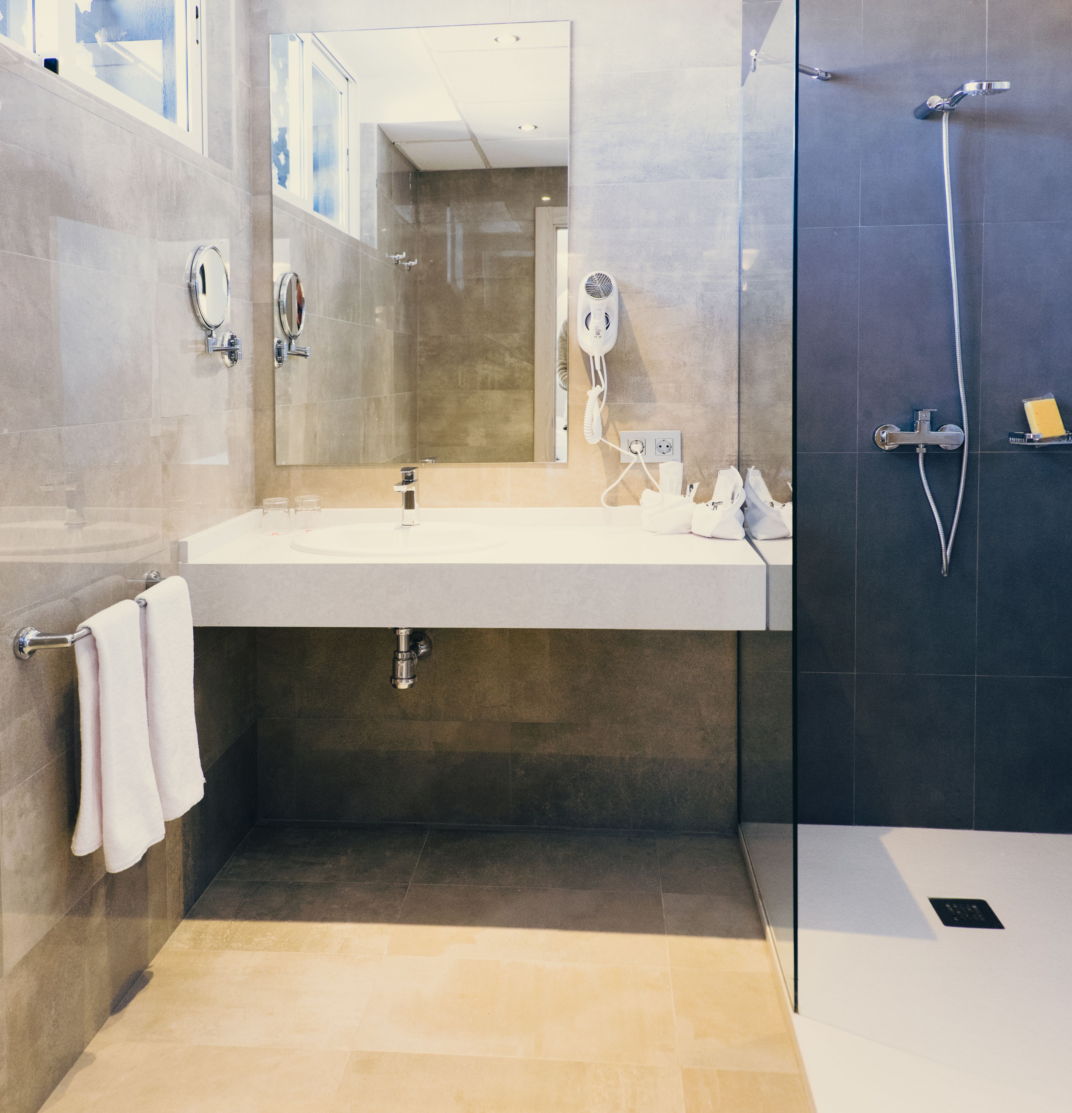 Un baño moderno con un espejo grande, un lavabo y una zona de ducha.