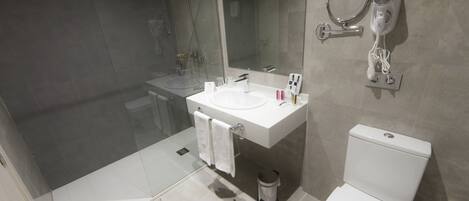 Un baño moderno con ducha de vidrio, lavamanos blanco y retrete.