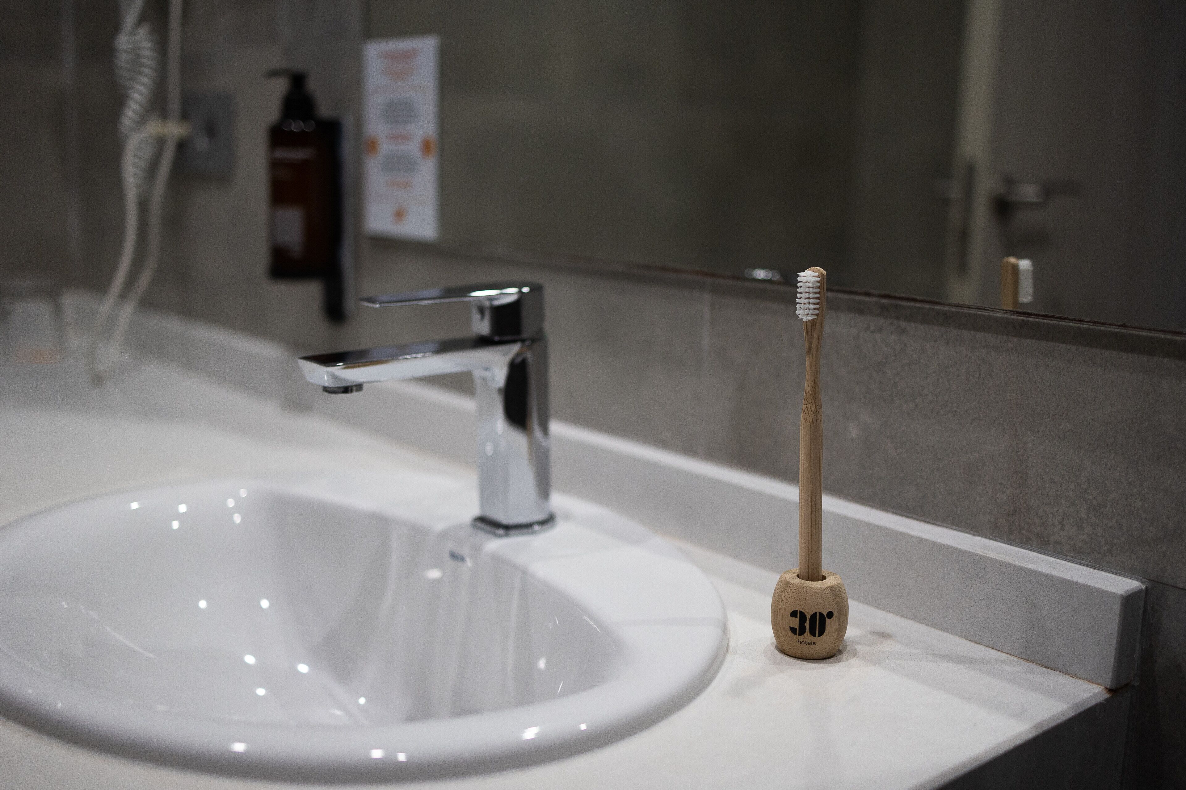 Un lavamanos con grifo cromado y un porta cepillos de dientes con un cepillo.