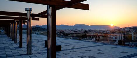 Une terrasse sur le toit offrant une vue sur le paysage urbain au coucher du soleil.