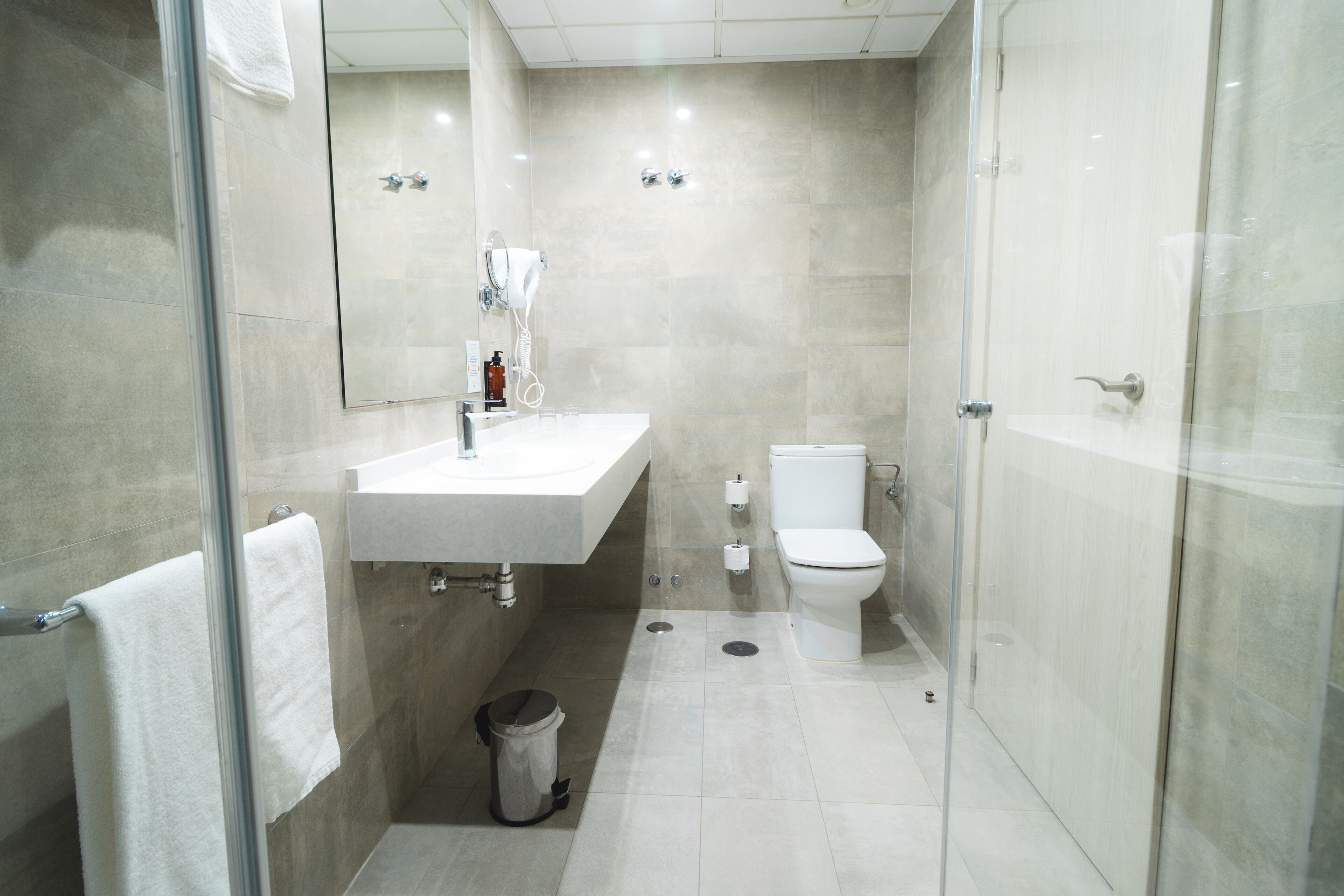 Een moderne badkamer met een douchecabine van glas, een witte wastafel en een toilet.